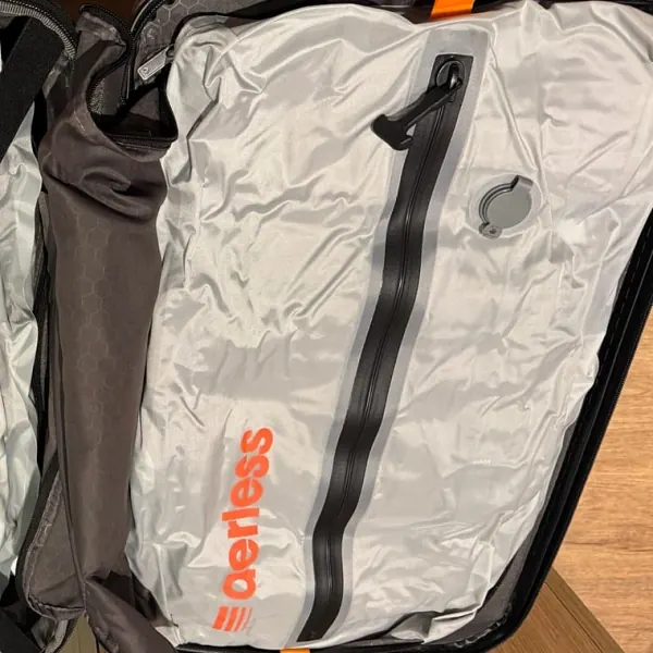 Flat compressed Aerless bag with black zipper packed inside a dark suitcase